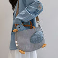 Blue check duck tote bag with stuffed polka-dot head worn on the shoulder
