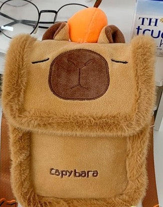 Brown plush capybara flap pouch with a tangerine on its head, front view
