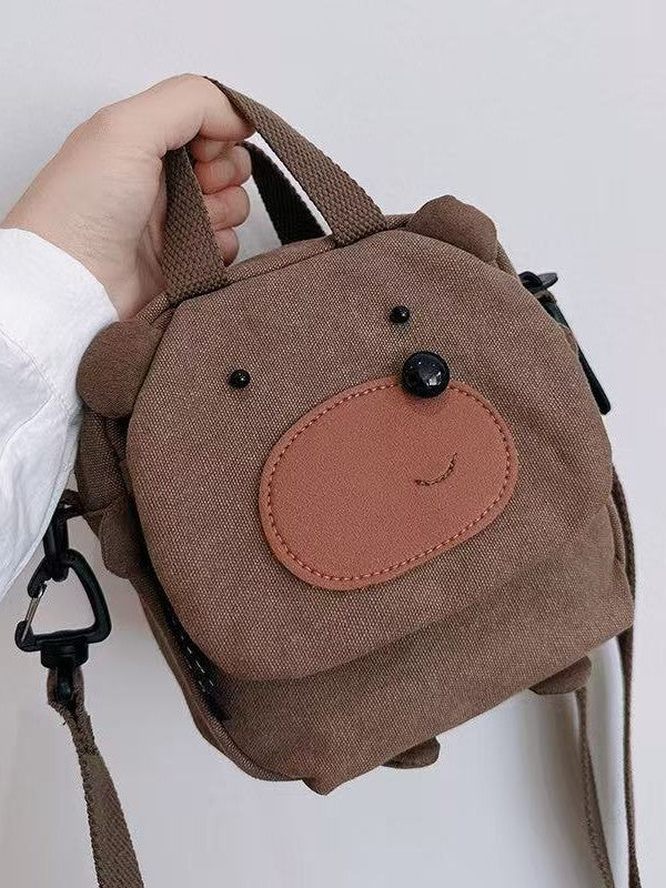 Brown bear canvas crossbody bag held by its top handles, front view