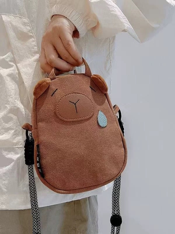 Brown canvas capybara phone bag with plush ears and blue teardrop, front view