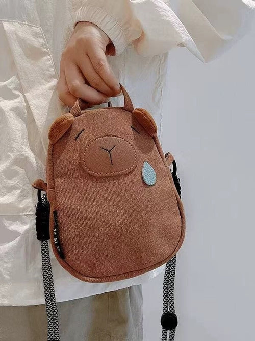 Brown canvas capybara phone bag with plush ears and blue teardrop, front view