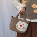 Plaid cat tote handbag with red pom-pom nose, held by the handles