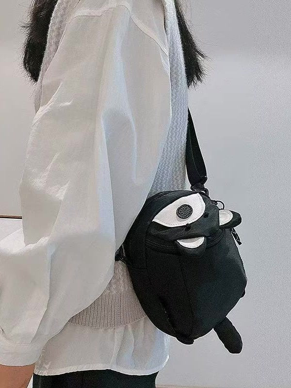 Black raccoon bag worn crossbody at the hip with tail hanging below
