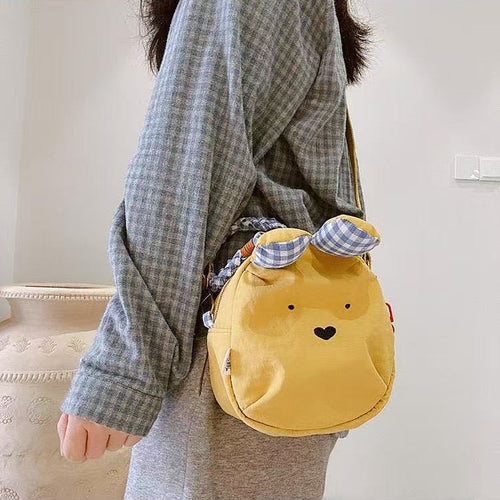 Yellow bunny crossbody bag with blue gingham ears worn at the hip