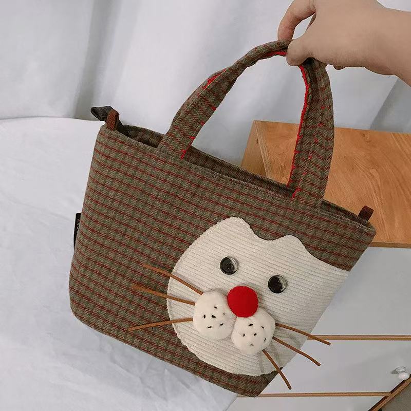 Close-up of the corduroy cat face, button eyes and whiskers on the plaid tote