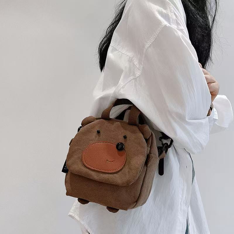Bear cube bag worn on the shoulder, showing its boxy shape and little feet