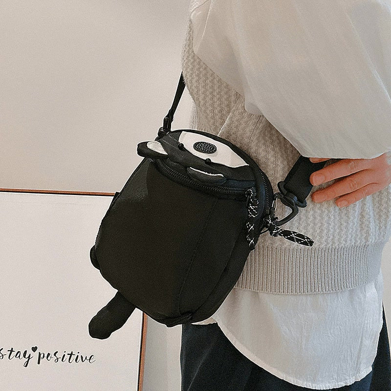 Black raccoon bag seen from above showing zip-top lid and strap clip