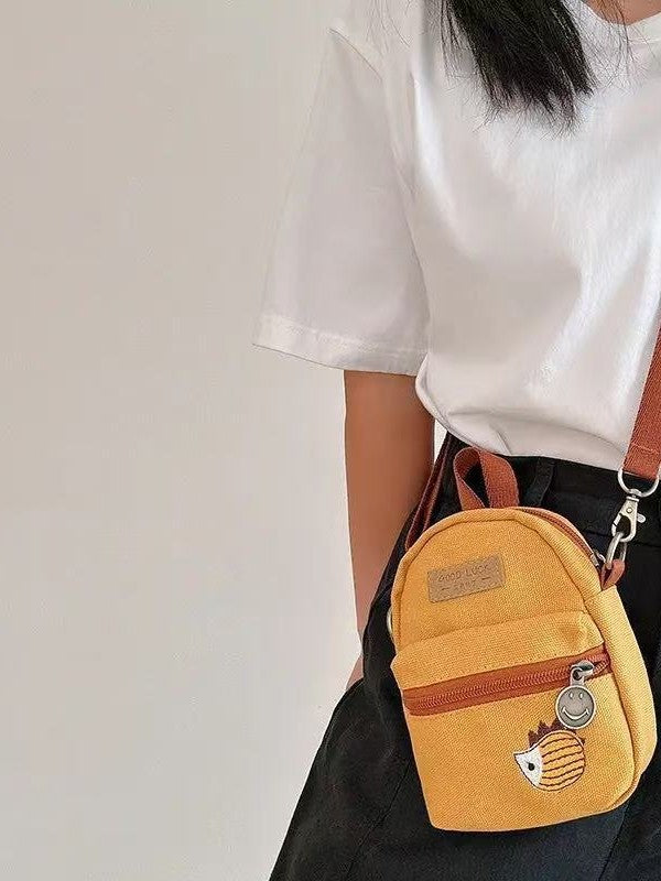 Yellow hedgehog crossbody bag worn at the hip with a white tee