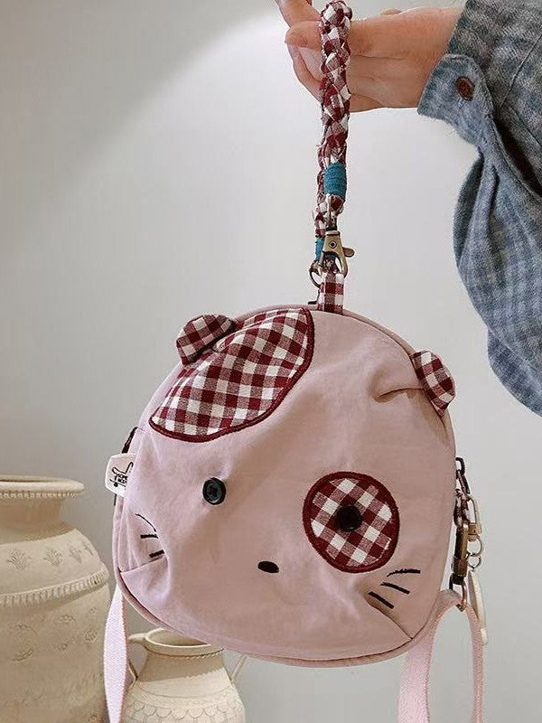 Pink patch cat bag held up by its braided gingham handle