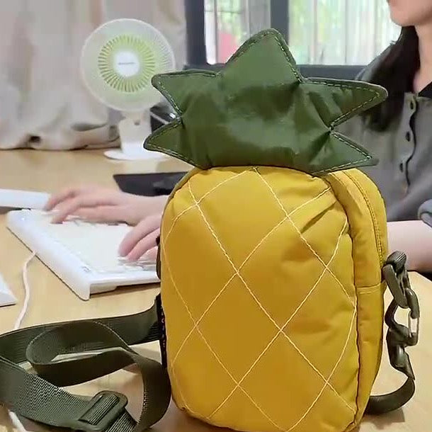 Pineapple crossbody bag standing on a desk with its strap