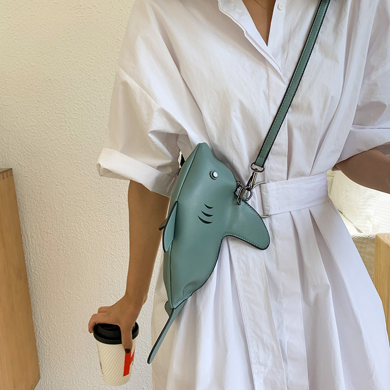 Sage green shark bag worn crossbody over a white shirt dress