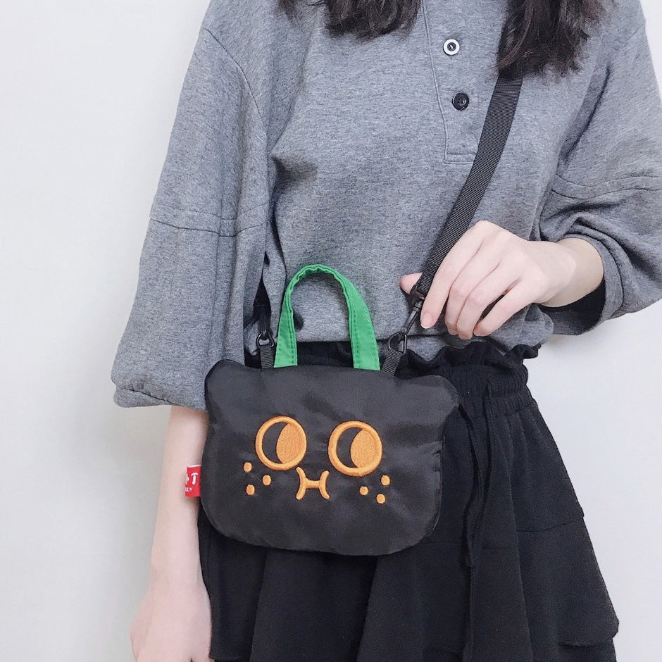 Cat phone bag worn crossbody over a grey top and black skirt