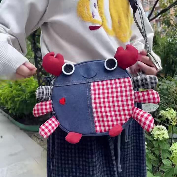 Denim crab crossbody bag worn outdoors, front view